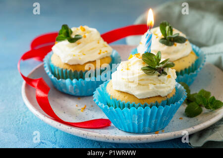 Bunte Kuchen mit Schlagsahne, Mohn und Orangenschale auf einem blauen Stein oder Schiefer Hintergrund. Stockfoto