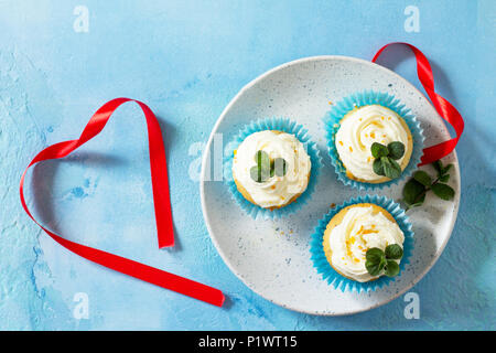 Bunte Kuchen mit Schlagsahne, Mohn und Orangenschale auf einem blauen Stein oder Schiefer Hintergrund. Stockfoto