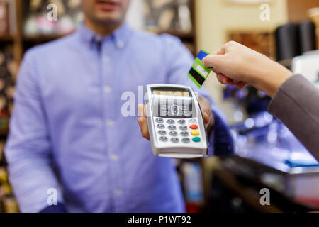 Foto des Verkäufers mit Terminal in Händen und Käufer mit der Kreditkarte. Stockfoto