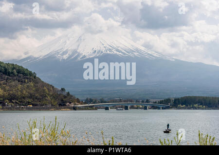 Fischer auf einem Boot auf dem See Kawaguchi mit dem Berg Fuji im Hintergrund mit Schnee bedeckt und von Wolken verhüllt, Japan Stockfoto