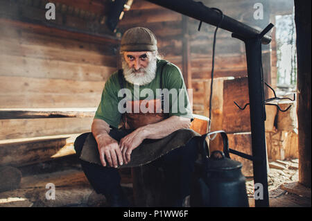 Alte Bart Förster in Dickey in der Scheune sitzen Stockfoto