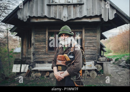 Alten bärtigen Förster vor der alten Holzhütte posing Stockfoto