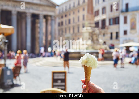 Erntegut Hand, die Kegel mit köstlichen Eis auf unscharfen Hintergrund des Square in der Nähe des Pantheon in Rom, Italien Stockfoto
