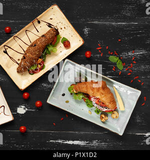 Drei verschiedene leckere Sandwiches mit Gemüse, Salat, Pilzen und Sauce liegen auf flachen, rechteckigen Platten auf Blau gealterte Holzoberfläche. Köstliche b Stockfoto