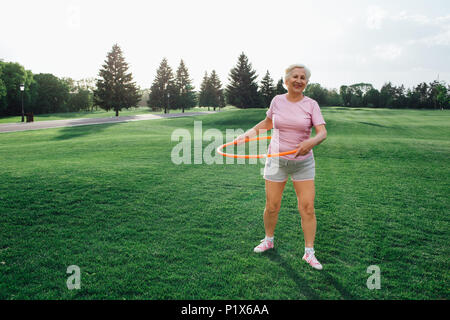 Ältere Frau nicht die Übung mit Hula Hoops Stockfoto