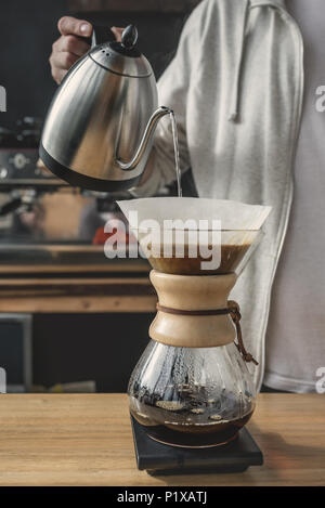 Nahaufnahme der unkenntlich Barista strömenden heißen Wasser in chemex. Kaffee brühen Konzept Stockfoto