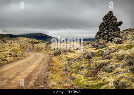 Unbefestigte Straße durch grüne Moos bedeckt Berserkjahraun Lavastrom und Cairn, Halbinsel Snaefellsnes, West Island, Island Stockfoto