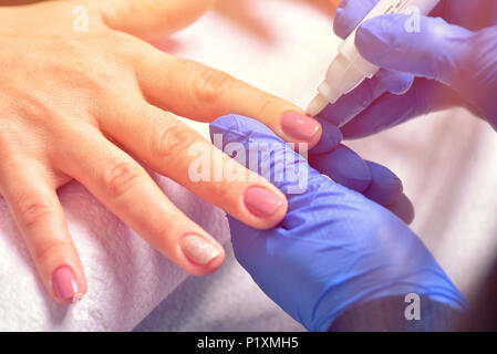 Nagelpflege und Maniküre. Nahaufnahme der Schöne weibliche Hände Anwendung transparenter Nagellack auf gesunde Nägel natürliche Frau im Beauty Salon. Manicuris Stockfoto