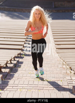 Foto des lockigen Haaren athletische Frau durch den Park laufen unter den Bänken Stockfoto