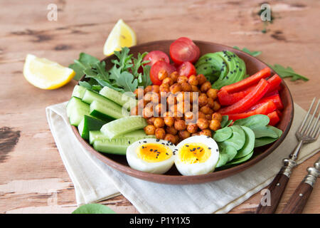 Buddha Schüssel, gesunde und ausgewogene Ernährung. Frittierte Kichererbsen, Tomaten, Gurken, Paprika, Eier, Spinat, Rucola. Stockfoto