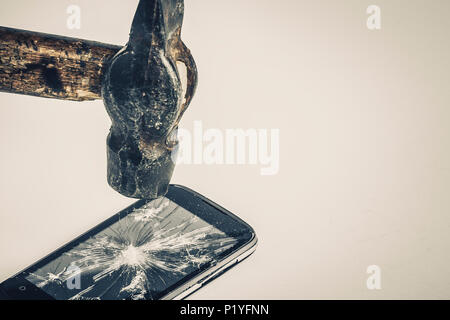 Schwarz Handy ist beschädigt, auf weißem Hintergrund, Hammer auf dem Bildschirm nach dem Schlagen, getönten Bild Stockfoto