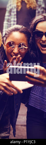 Weibliche Freunde auf der Suche nach smart phone Stockfoto