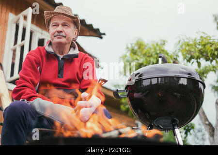 Grill Zeit. Europäischen Mann in hat Warten auf Gegrilltes. Stockfoto