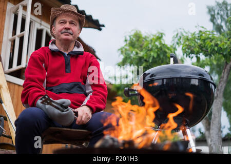 Grill Zeit. Europäischen Mann in hat Warten auf Gegrilltes. Stockfoto