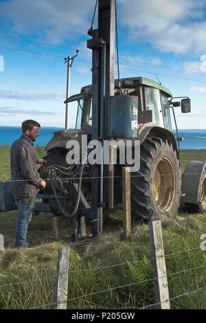 dh Posts Zaun Rammmaschine LANDWIRTSCHAFT Großbritannien Traktor Feldmaschinen Landwirt Betrieb nach hydraulischem Stampfer Barbwire Fechten Farmarbeiter Menschen Bauernhof Stockfoto