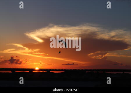 Die Silhouette eines ausgeschalteten Gleitschirm, Motorschirm, vor einem orange sky im Süden von Texas, USA. Die Sonne in der Dämmerung mit einer Gewitterwolke cumulonimbus. Stockfoto