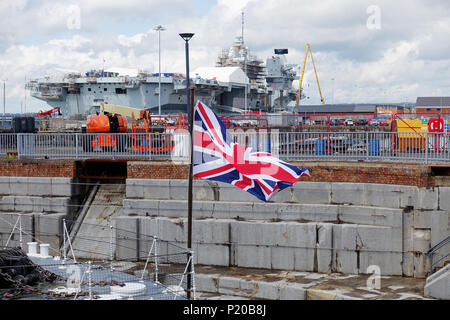 Union Jack auf der Jackstaff des Museums Schiff HMS M33 mit newmaircraft Träger HMS Queen Elizabeth, die sich Änderungen am Portsmouth Dockyard Stockfoto