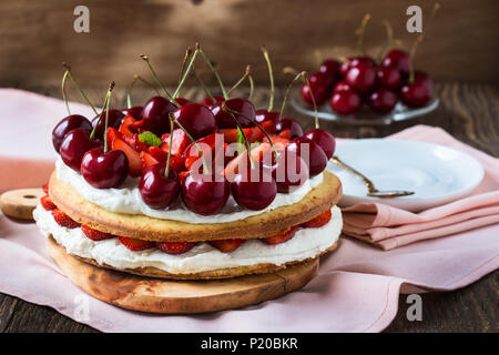 Hausgemachte Sahne Torte, frisch, bunt, und leckeres Dessert mit saftigen Erdbeeren, süßen Kirschen und Schlagsahne Stockfoto