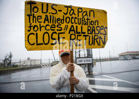 NAGO, JAPAN - Juni 14: Anti-US-base Demonstrant hält ein Plakat protestieren außerhalb der US-Base Camp Schwab am 14. Juni 2018 in Nago, Präfektur Okinawa, Japan. Die demonstranten Bühne sitzen - aus Protest gegen das Tor des US Marine Corps' Camp Schwab in der Henoko Bezirk von Nago Sperrung der Durchfahrt von Fahrzeugen, die von der japanischen Regierung für die Verlegung der Bauarbeiten des neuen US-Marines Airbase Station Futenma mobilisiert. (Foto: Richard Atrero de Guzman/LBA) Stockfoto