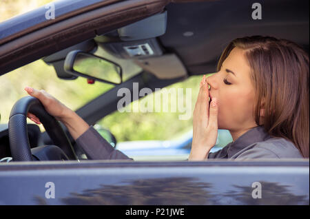 Seitenansicht des Jungen casual Frau Gähnen und müde, während im Auto sitzen und Fahren im Tageslicht. Stockfoto