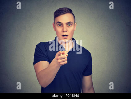 Legerer Mann geschockt und Kamera entschlossen zeigen. Stockfoto