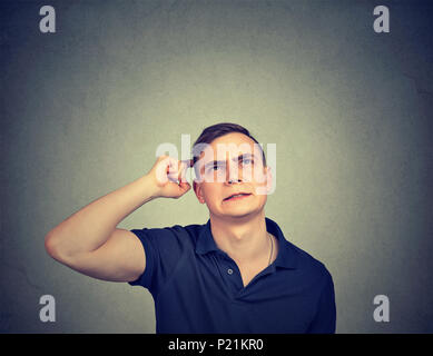 Closeup Portrait man kratzen Kopf, Gedanken über etwas, bis suchen, auf grauen Hintergrund. Stockfoto