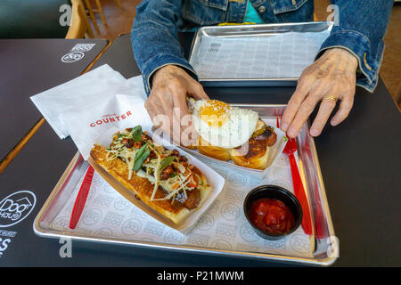 Eine Speck umwickelt Hund mit einem "One Night in Bangkok" bauen, Vordergrund als Kunde ihr Rindfleisch Hot Dog nimmt mit einem 'Little Mule' an der Hund das Haus auf den Tag der Eröffnung der ersten New Yorker store am Dienstag, 12. Juni 2018. Waren die Besucher zu einer kostenlosen Hot Dog als Willkommen in Ihrem neuesten Standort in Soho behandelt. Die Kette ist spezialisiert auf fast Casual Dining von Hot Dogs, Würstchen, gegrillte Hähnchen und Burger King Hawaii Brötchen und gekrönt mit ihrer Unterschrift 'baut'. Hund Haus wurde im Jahr 2010 in Pasadena gegründet, Caifornia mit Plänen zu 300 neue Franchisen 2023 öffnen. (© Richard B. Levine) Stockfoto