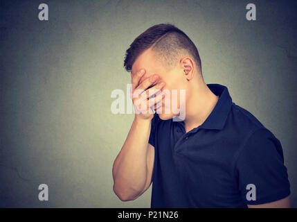 Traurig, deprimiert Mann mit der Hand auf das Gesicht nach unten schauen. Stockfoto
