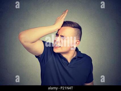 Mann, Slapping Hand auf den Kopf in eine duh Moment auf grauem Hintergrund. Negative menschliche Emotion Gefühl Stockfoto