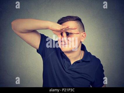 Man drückt mit den Fingern die Nase schaut mit Ekel etwas stinkt auf grauem Hintergrund. Stockfoto