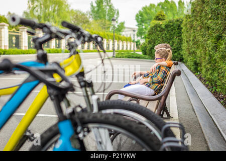 Kleine Kinder umarmen Während sitzt auf der Bank mit Fahrrädern in Vordergrund Stockfoto