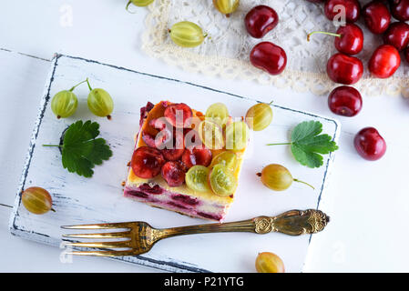 Käsekuchen mit Kirschen Beeren und hausgemachten Quark, mit Stachelbeere auf weißem Holz- Board eingerichtet, Ansicht von oben Stockfoto