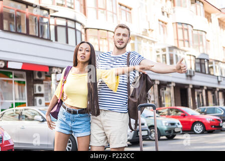 Jungen multiethnischen Paar Touristen mit Koffer hageln Taxi in der Stadt Stockfoto