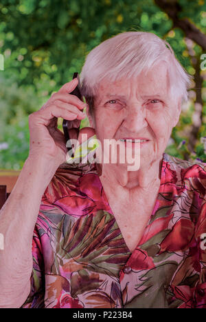 Niedlich, ältere Frau im Gespräch über ein Mobiltelefon in den Garten. Stockfoto