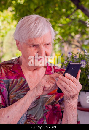 Lächelnde ältere Frau Telefon Nummer eins ihrer Verwandten. Stockfoto