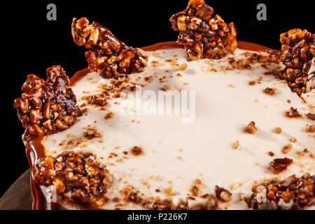 Runde weiße Kuchen mit Karamell und Schokolade Puffreis auf ein rundes Tablett auf schwarzem Hintergrund Stockfoto