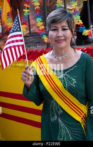 Ein Einwanderer tragen eines Süd Vietnam Schärpe winkt eine amerikanische Flagge bei der Vietnamesischen Amerikanischen kulturellen Parade. Stockfoto