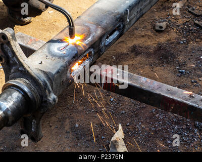 Metall arbeiten. Man schneidet ein Loch in einen Stahl Stück mit gas schweißen Stockfoto