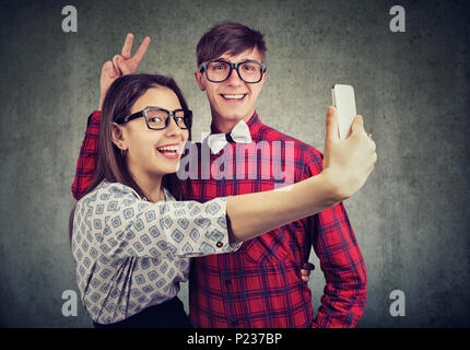 Cute Glücklich der Mann und die Frau in der Gläser zusammen und unter selfie mit Smartphone Spaß. Stockfoto