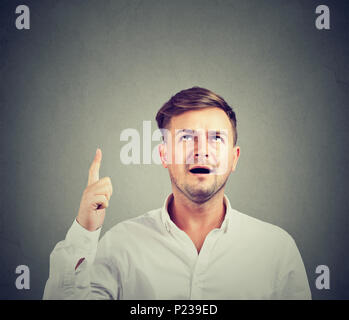 Junger Mann auf der Suche oben in Lösung und tolle Idee auf grauem Hintergrund. Stockfoto