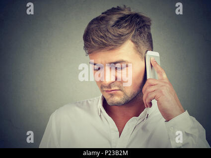 Junge unglückliche Menschen in Depression sprechen am Telefon und mit schlechten Nachrichten auf grauen Hintergrund. Stockfoto