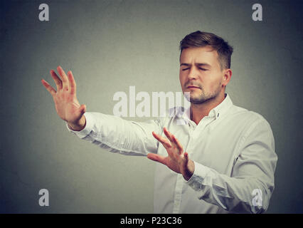 Junger Mann mit geschlossenen Augen Pushing Hands vorwärts gehen im Dunkeln mit Hilfe der Intuition. Stockfoto