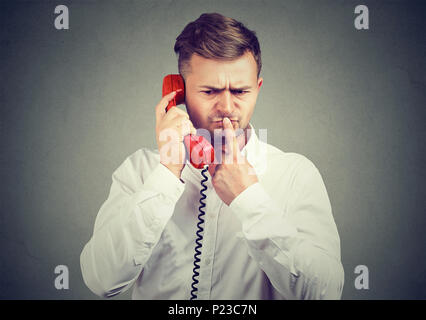 Nachdenklicher Mann im weißen Hemd sprechen am Telefon und berühren Lippen in Zweifel in verwirrende Nachrichten. Stockfoto