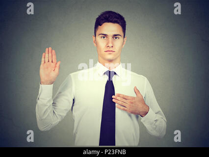 Stattliche business Mann, einen Eid Versprechen auf grauem Hintergrund Stockfoto