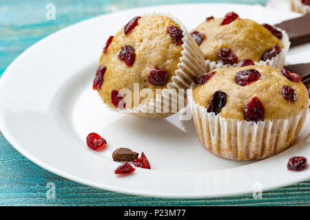 Vanille Muffins mit getrockneten Kirschen auf den weißen und blauen Holzmöbeln rustikal Tisch. Schokolade Stockfoto