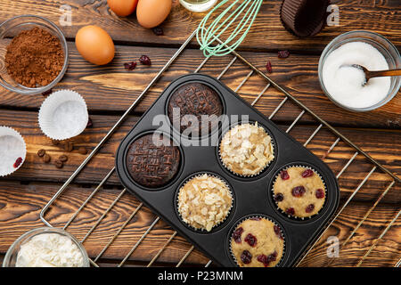 Der Prozess der Herstellung Muffins in hellen Silikon Formen. Kochvorgang. Vorbereitung. Zutaten und fertige verschiedene Cupcakes Stockfoto