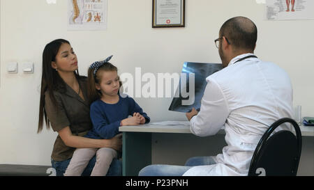 Arzt erklärt die Brust röntgen Bild der Mutter, die kleine Tochter in die Arme Stockfoto