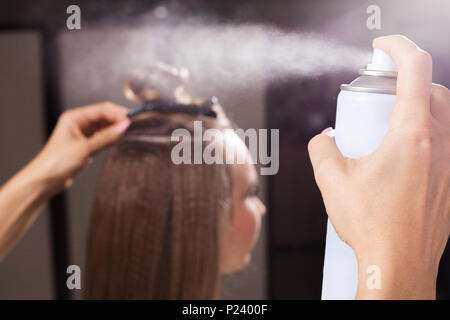 Friseur zur Festsetzung einer haarschopf einer Frau mit Haarspray Stockfoto