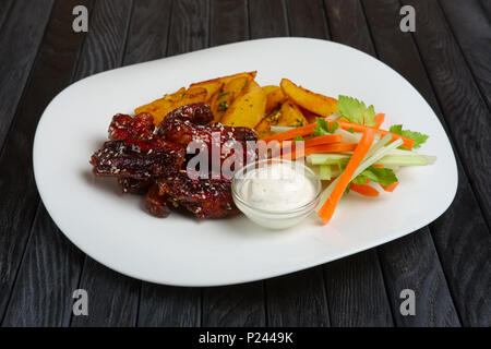 Buffalo Chicken Wings mit gebratenen Kartoffeln und Karotten und Sellerie sticks Stockfoto