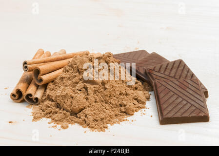 Dark Chocolate und Cinnamon Sticks und Pulver auf hölzernen Hintergrund Stockfoto